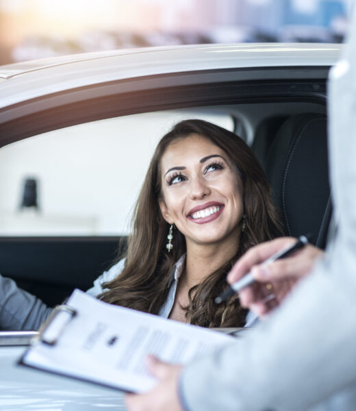 Happy customer buying brand new car at local car dealership.