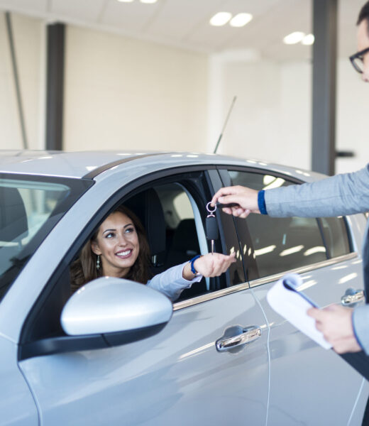 Vehicle dealer handing over keys to the new car owner.